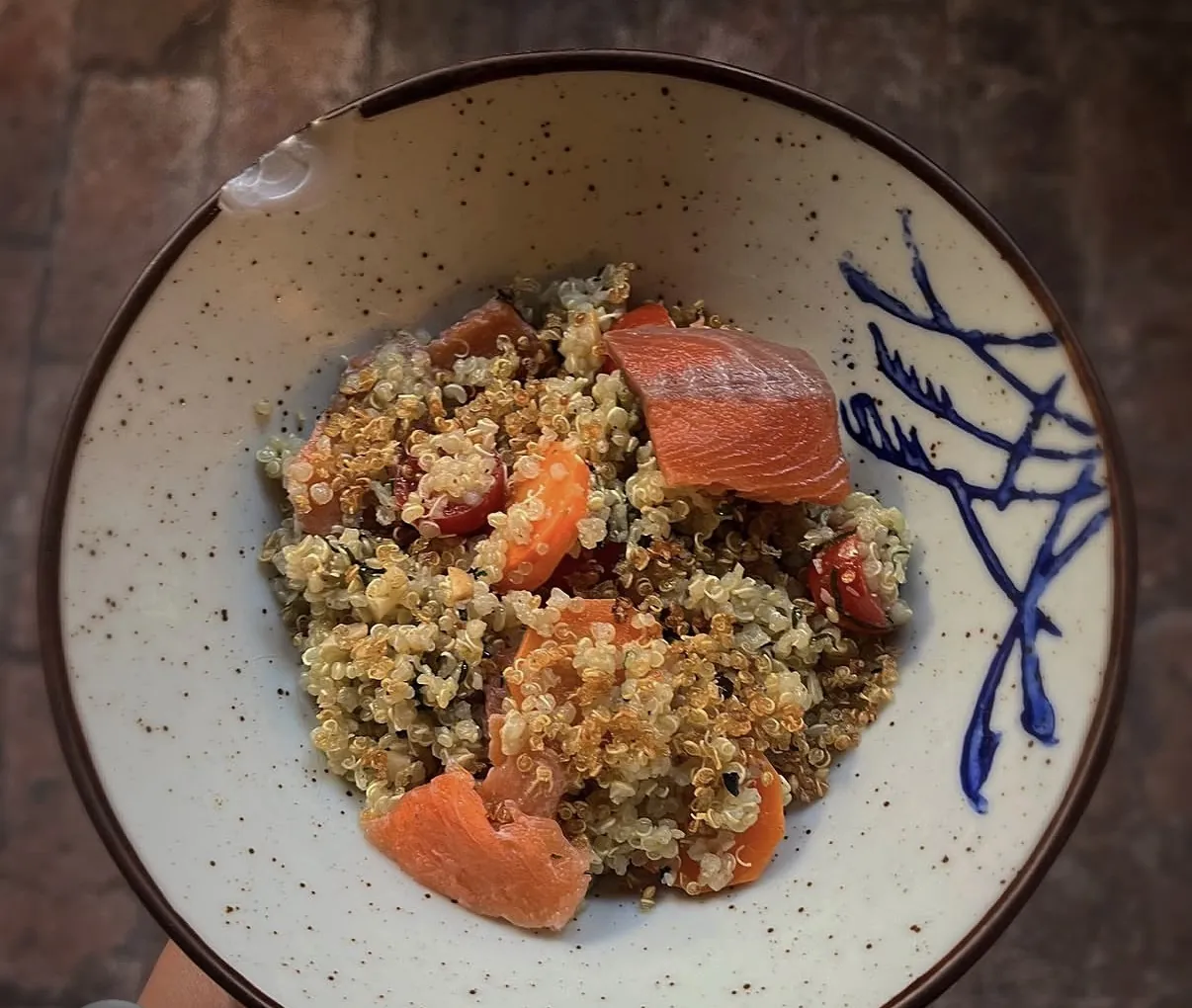 Quinua con salmón curado y cítricos en plato de cerámica pintada